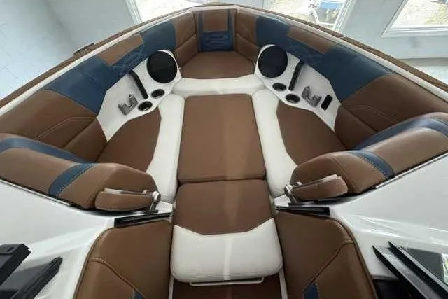 Slide: The Image of 2023 Malibu Wakesetter 25 LSV interior with brown and white seating, cup holders, and speakers. - 7