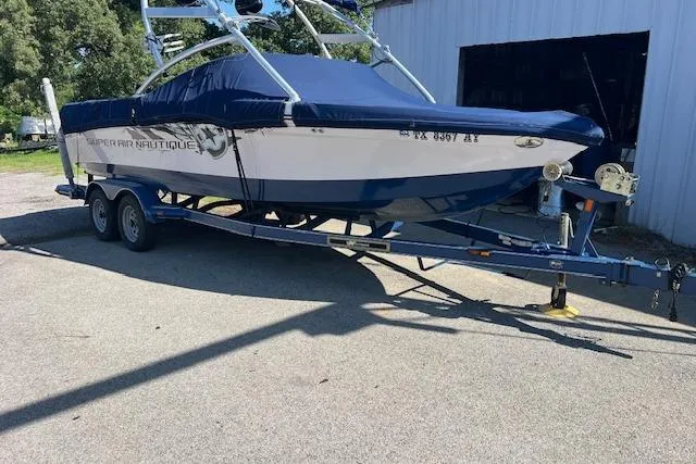 Slide: The Image of 2008 Nautique Super Air Nautique 230 boat on trailer, covered and parked outdoors. - 1