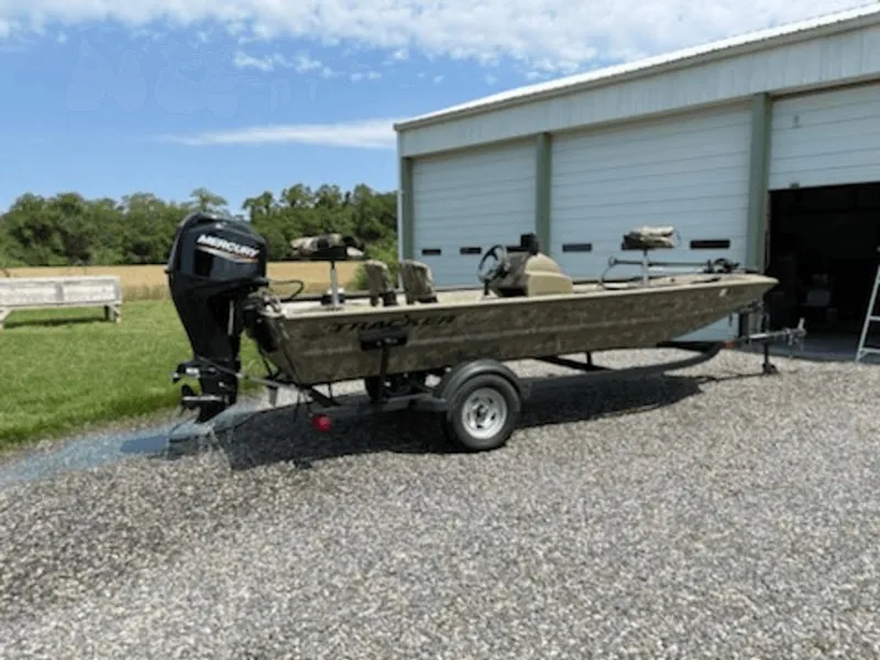 Slide: The Image of 2023 Tracker MVX 1754 boat on trailer outside garage. - 2