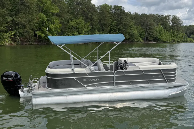 Slide: The Image of 2023 Godfrey Sweetwater 2286 C pontoon boat on a serene lake. - 6
