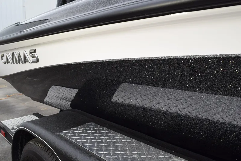 Slide: The Image of 2027 Caymas 201 Pro boat with sleek black and white design on a diamond plate trailer. - 5