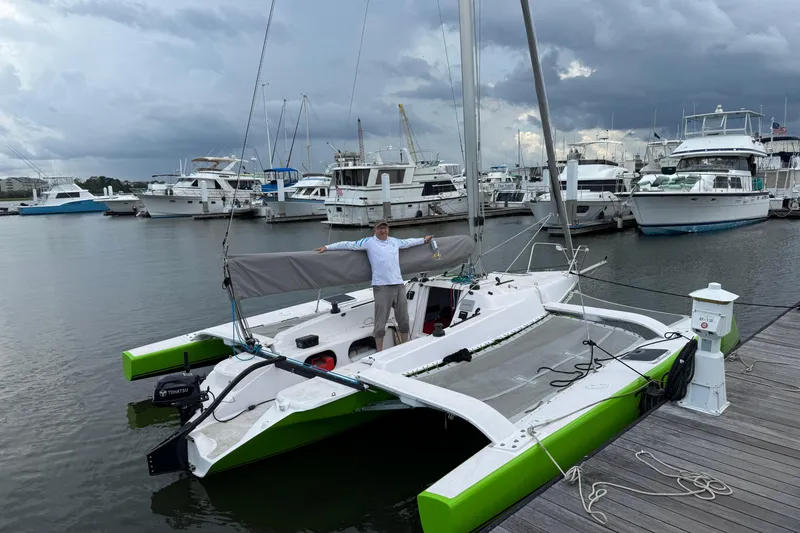 Slide: The Image of Man standing on Corsair 760R trimaran at marina, cloudy sky in background. - 4