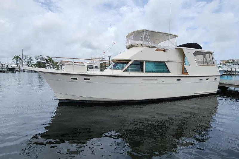 The Image of 1983 Hatteras 48 Motor Yacht docked in a marina under cloudy skies. - 0