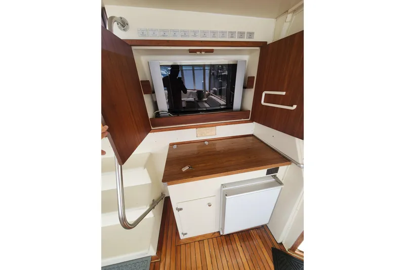 Slide: The Image of 1983 Hatteras 48 Motor Yacht interior with wooden cabinetry and compact refrigerator. - 13