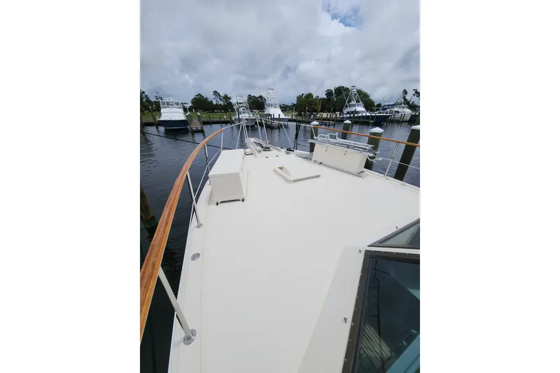 Slide: The Image of 1983 Hatteras 48 Motor Yacht docked, showcasing spacious deck and marina view. - 6
