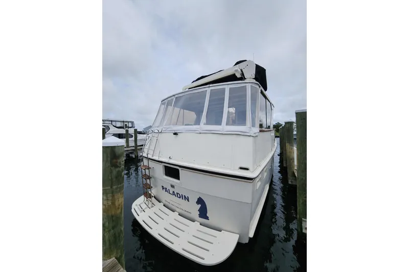 Slide: The Image of 1983 Hatteras 48 Motor Yacht docked, rear view with enclosed deck and "Paladin" name. - 8