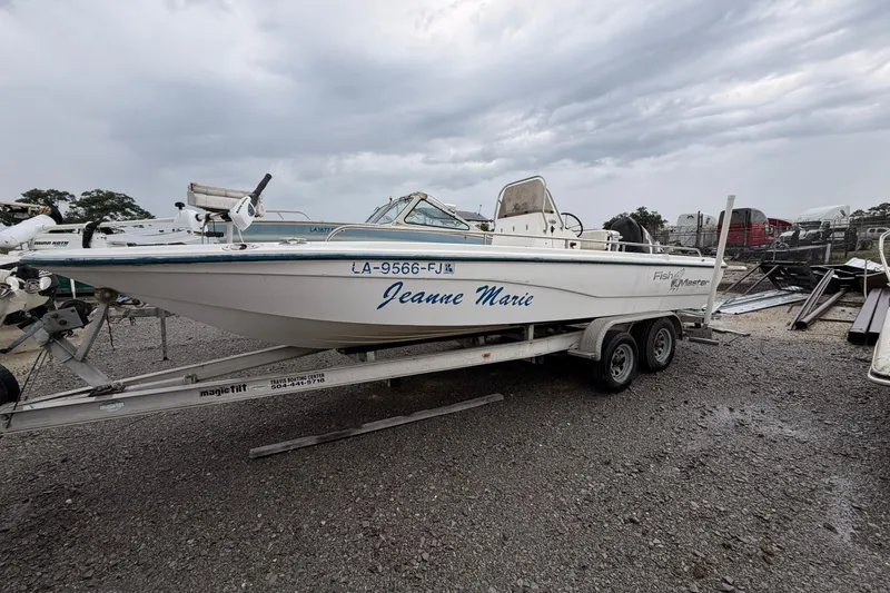 Slide: The Image of 2004 Fishmaster 24 boat named "Jeanne Marie" on a trailer in a gravel lot. - 2