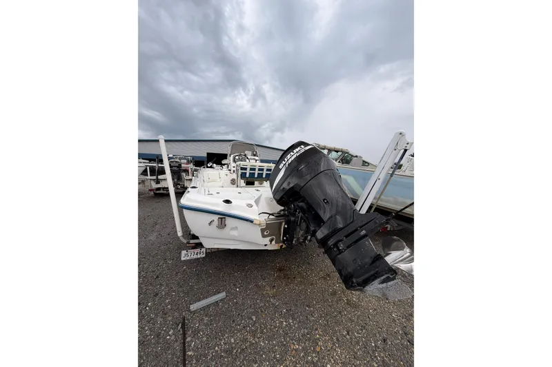 Slide: The Image of 2004 Fishmaster 24 boat with Suzuki outboard motor, parked on gravel under cloudy skies. - 3