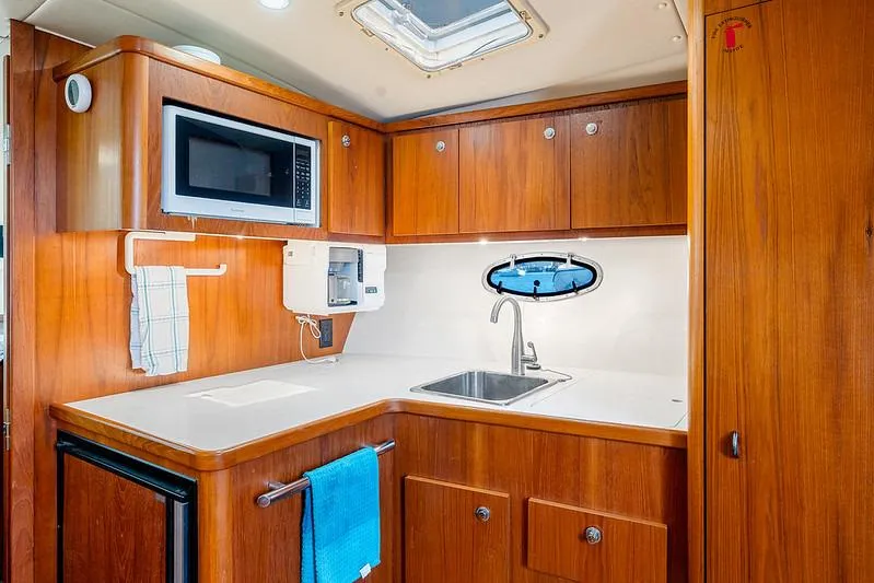 Slide: The Image of 2000 Tiara 3500 EXPRESS yacht kitchen with wood cabinets, sink, microwave, and porthole window. - 36
