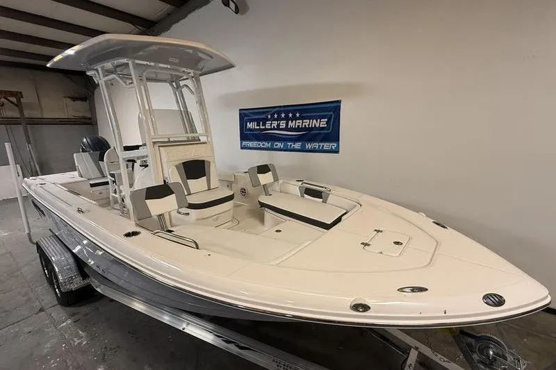 Slide: The Image of 2026 Robalo 226 Cayman boat displayed indoors at Miller's Marine showroom. - 2
