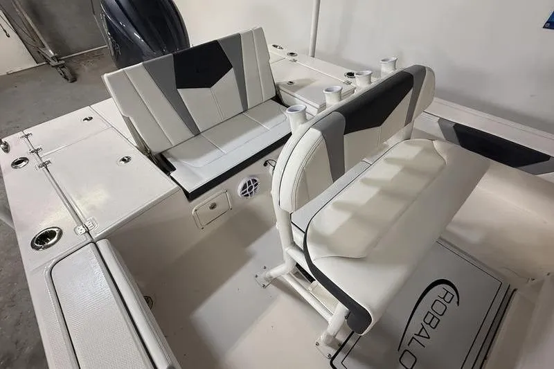 Slide: The Image of 2026 Robalo 226 Cayman boat interior with cushioned seating and rod holders. - 7