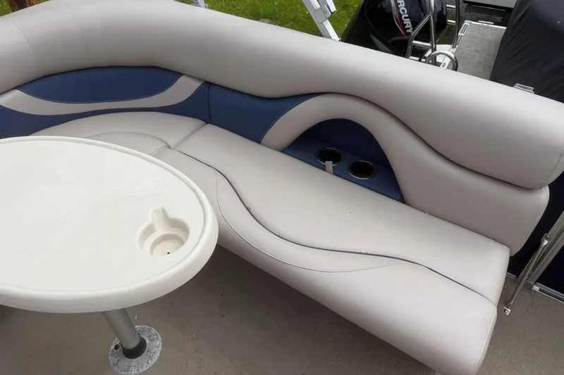 Slide: The Image of 2014 Sylvan Mirage Cruise 818 CR boat interior with cushioned seating and table. - 8