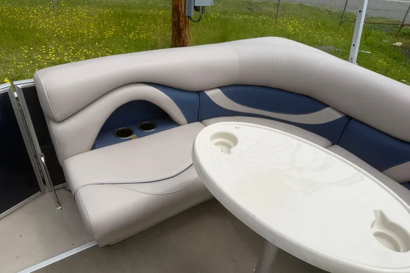 Slide: The Image of 2014 Sylvan Mirage Cruise 818 CR boat interior with cushioned seating and table. - 9