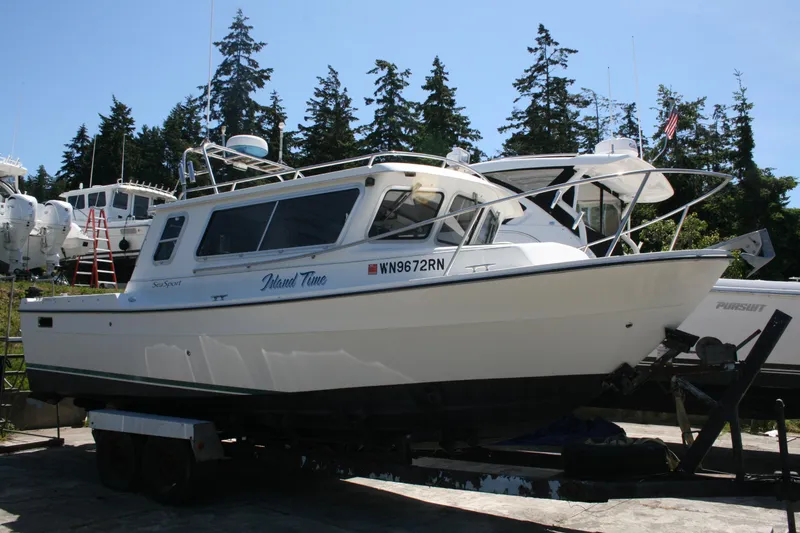 The Image of 2002 Sea Sport Explorer 2400 boat on trailer, surrounded by trees and other boats. - 0