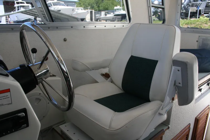 Slide: The Image of Captain's chair and steering wheel inside a 2002 Sea Sport Explorer 2400 boat. - 2