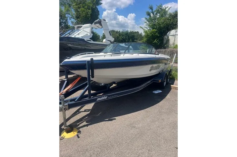 Slide: The Image of 2000 Malibu Sunsetter VLX boat on trailer, parked outdoors under a sunny sky. - 2