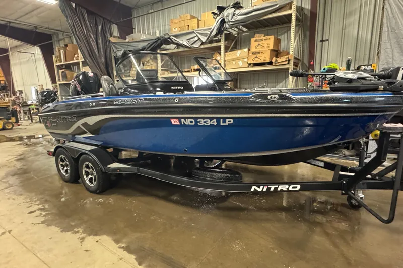 Slide: The Image of 2021 Nitro ZV19 Sport boat in a workshop, blue hull, on a trailer. - 2