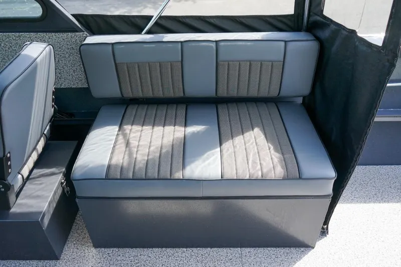 Slide: The Image of 2026 Alumaweld X202 Stryker boat interior seating with gray upholstery and storage compartment. - 11