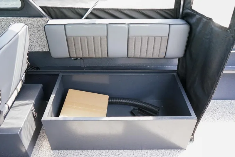 Slide: The Image of 2026 Alumaweld X202 Stryker boat interior storage compartment with box and hose. - 12