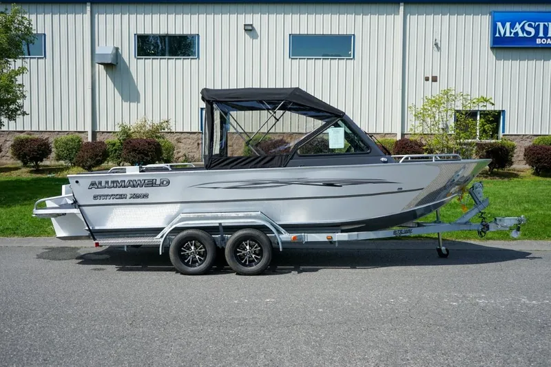 Slide: The Image of 2026 Alumaweld X202 Stryker boat on trailer, parked outdoors near building. - 2