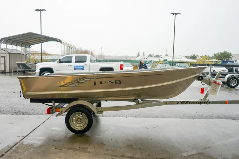 Slide: The Image of 2021 Lund WC-12 boat on trailer in outdoor dealership lot. - 12