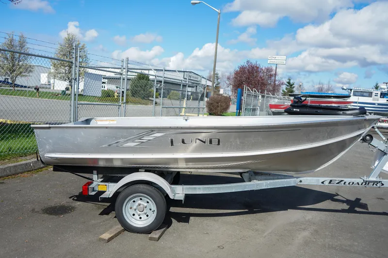 Slide: The Image of 2021 Lund WC-12 aluminum boat on trailer, parked outdoors under a blue sky. - 8