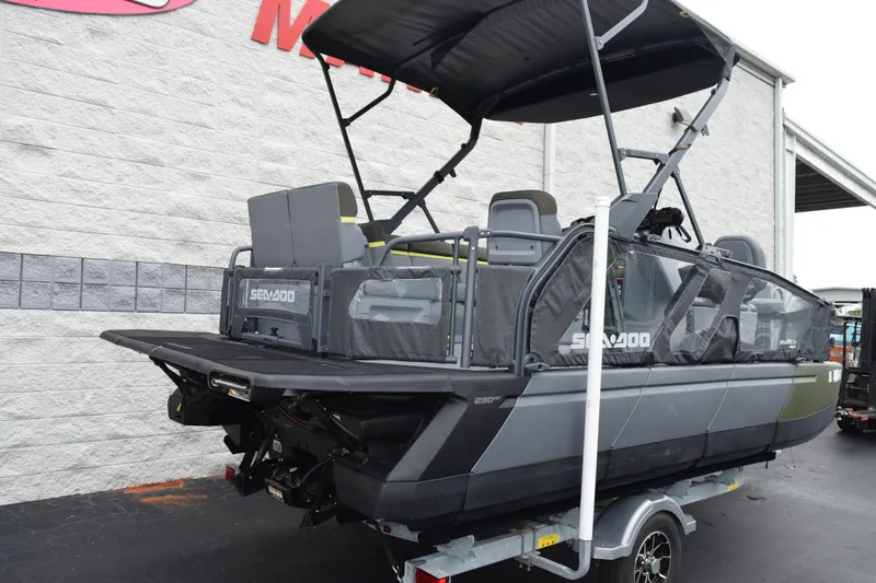 Slide: The Image of 2025 Sea-Doo Switch Fish 18 pontoon boat on trailer, parked outside a building. - 5