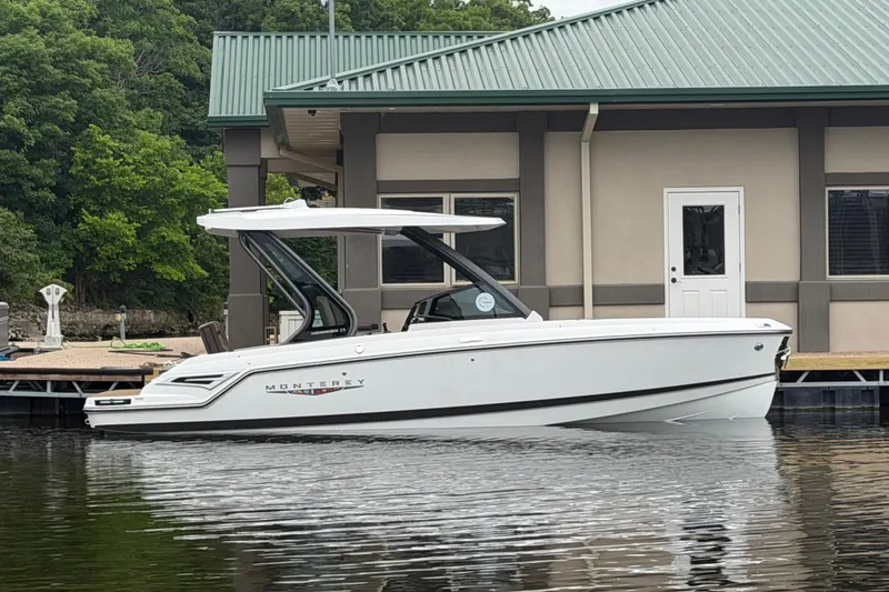The Image of 2026 Monterey Elite 25 SD boat docked by a building with green roof. - 1