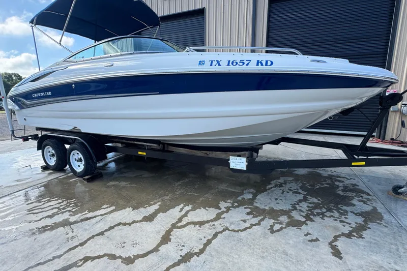 Slide: The Image of 2005 Crownline 240 EX boat on trailer, parked outside a building. - 2