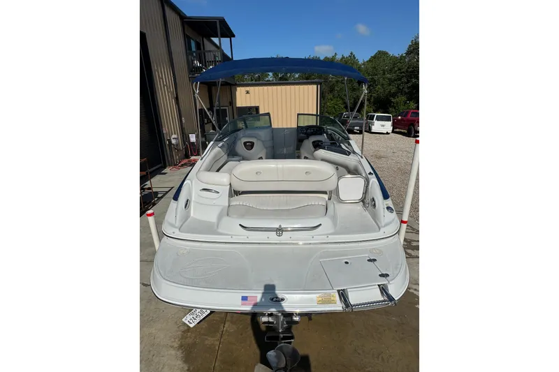 Slide: The Image of 2005 Crownline 240 EX boat with blue canopy, parked outdoors near a building. - 6