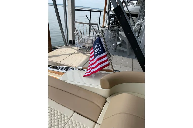 Slide: The Image of 2022 Chris Craft 28 Launch boat with American flag, docked by a serene waterfront. - 3