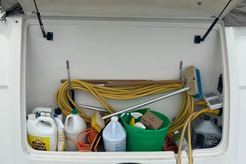 Slide: The Image of Storage compartment of a 2005 Chaparral Signature 350 boat with cleaning supplies and hoses. - 15