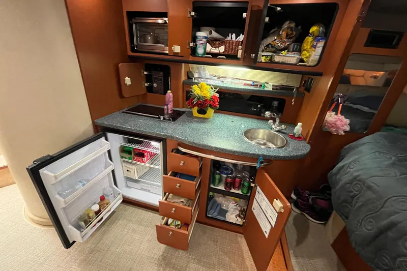 Slide: The Image of Compact kitchen area in a 2005 Chaparral Signature 350 boat, featuring open fridge and storage. - 39
