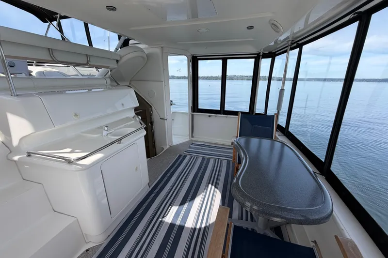 Slide: The Image of 1997 Sea Ray 370 Aft Cabin interior with table, chairs, and panoramic windows overlooking water. - 12
