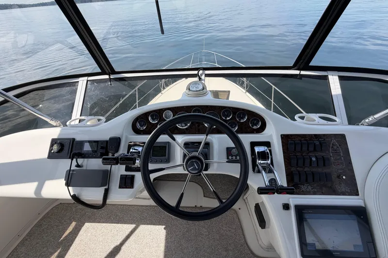 Slide: The Image of 1997 Sea Ray 370 Aft Cabin helm with steering wheel and control panel on calm water. - 7