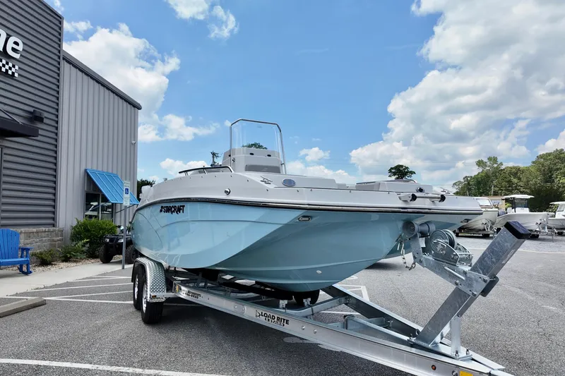 Slide: The Image of 2026 Starcraft SVX 211 OB CC boat on trailer, parked outdoors under a blue sky. - 3
