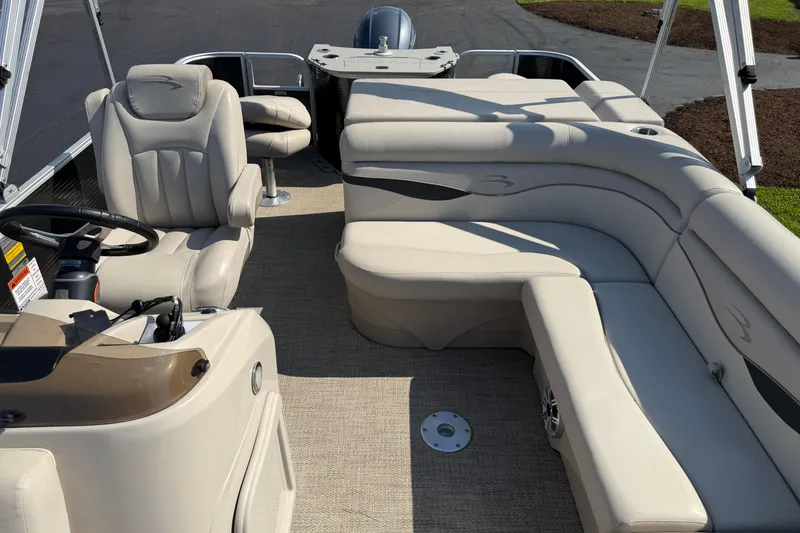 Slide: The Image of 2018 Bennington 21 SF pontoon boat interior with beige seating and steering console. - 2