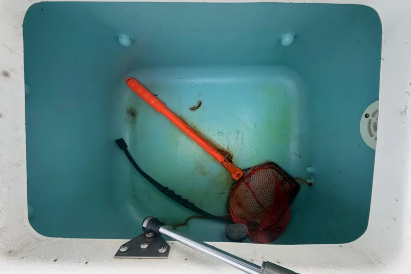 Slide: The Image of Storage compartment of 2018 Yamaha Boats 190 FSH with fishing net and handle. - 51