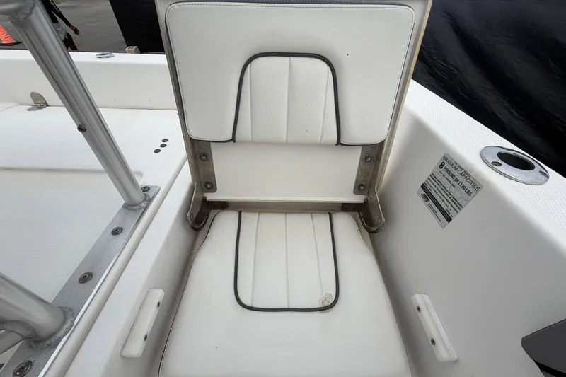 Slide: The Image of 2018 Yamaha Boats 190 FSH seat with white upholstery and capacity label. - 52