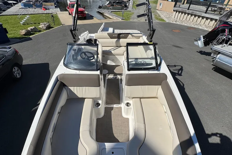 Slide: The Image of 2018 Bayliner 195 Deck Boat interior with spacious seating and dual consoles, docked near water. - 10