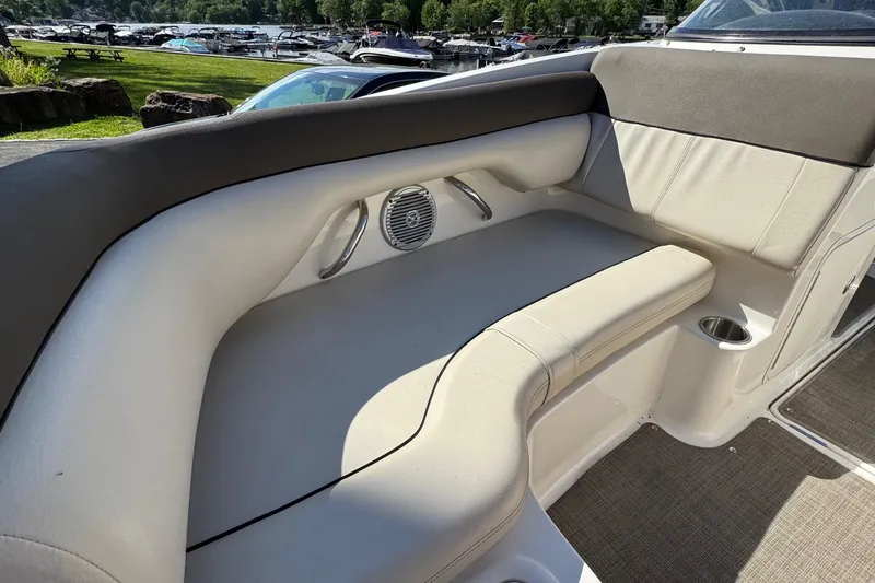 Slide: The Image of 2018 Bayliner 195 Deck Boat interior seating with speaker and cup holder, docked near a marina. - 9