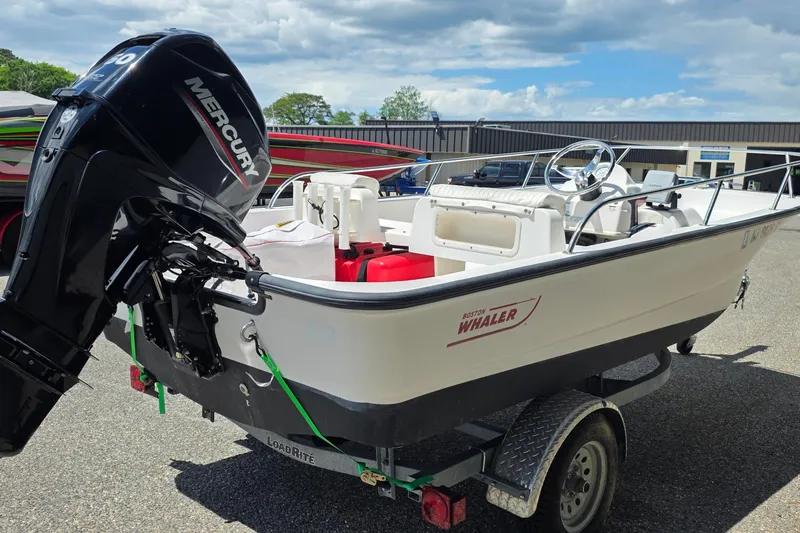 Slide: The Image of 2004 Boston Whaler 150 Sport boat with Mercury engine on trailer, outdoors. - 2