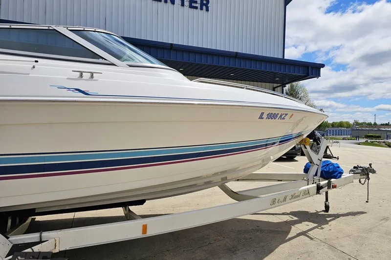Slide: The Image of 1997 Formula 252 SS boat on trailer, parked outside a building under a cloudy sky. - 4