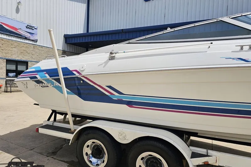 Slide: The Image of 1997 Formula 252 SS boat on trailer, featuring colorful stripes, parked outside a building. - 5