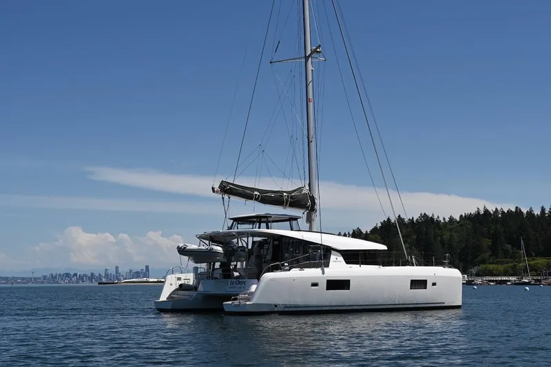 Slide: The Image of 2022 Lagoon 42 catamaran sailing on calm waters with city skyline in background. - 4