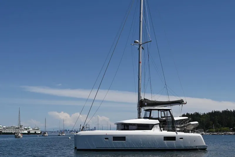 Slide: The Image of 2022 Lagoon 42 catamaran anchored in a serene harbor under a clear blue sky. - 9