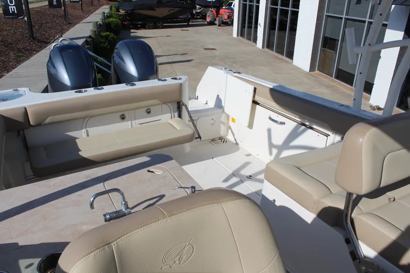 Slide: The Image of 2017 Sailfish 275 DC boat interior with beige seating and dual outboard motors. - 11