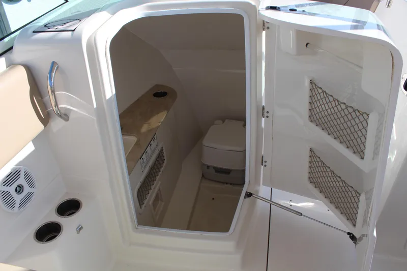Slide: The Image of 2017 Sailfish 275 DC boat interior with open storage compartment and portable toilet. - 18
