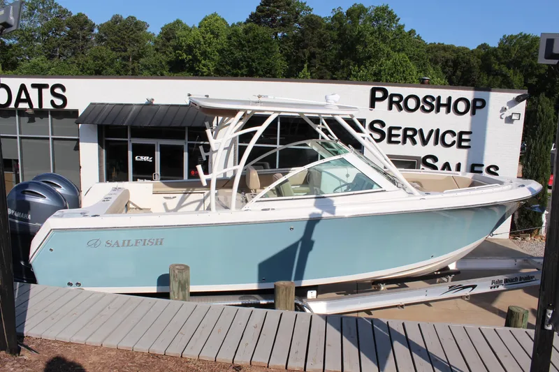 Slide: The Image of 2017 Sailfish 275 DC boat displayed at a dealership with service and sales signage. - 2