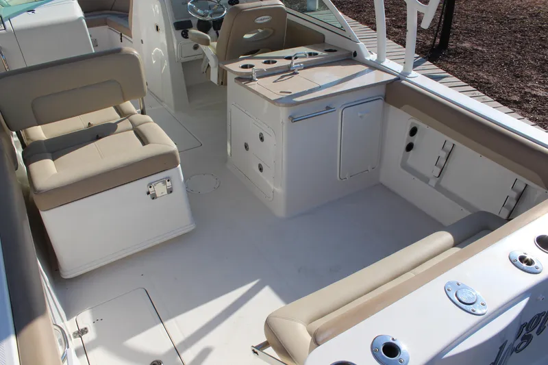 Slide: The Image of 2017 Sailfish 275 DC boat interior with beige seating and storage compartments. - 9